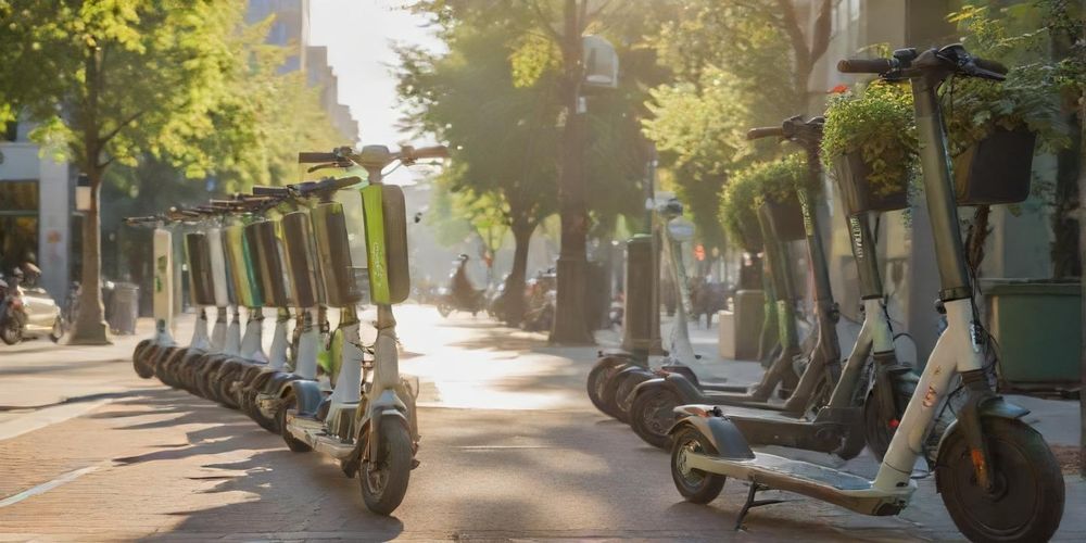 A close-up, vivid image of shared electric scooters and bicycles lined up in a vibrant urban area, highlighting eco-friendly transport solutions with happy users in the background during a sunny afternoon.
